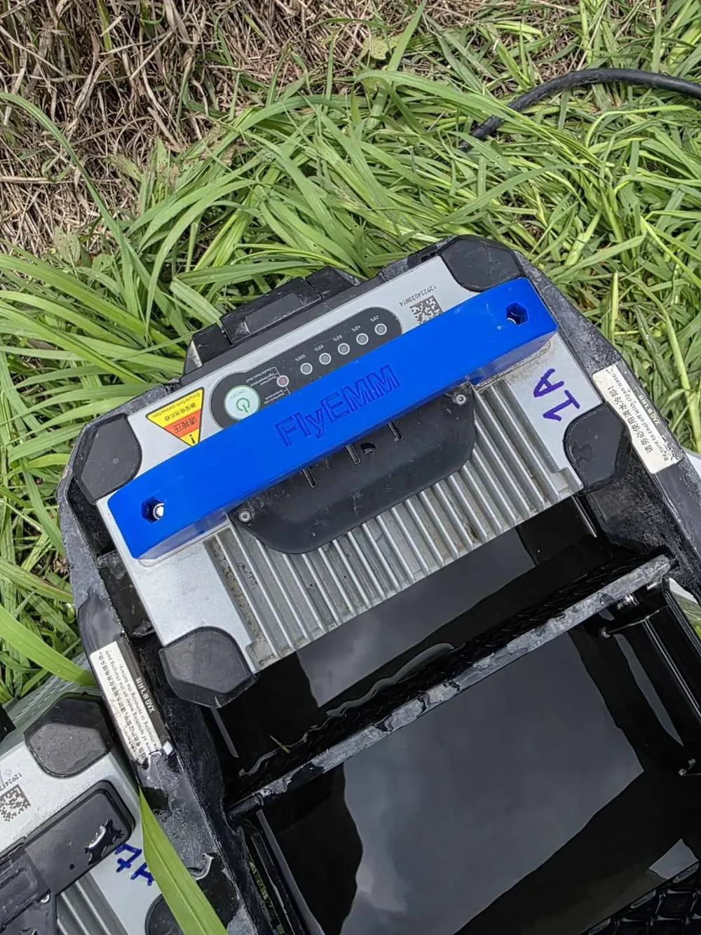 A 3D-printed carry handle fitted to a drone flight battery, printed with the operator name.
